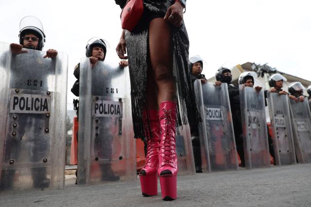 A transgender sexual worker stands in front of Mexican riot police officers during a protest against the Gran Tenochtitlan bike path and the organisation of the World Cup in Mexico City on April 19, 2026. The Gran Tenochtitlan is an infrastructure project designed to connect Banorte Stadium (formerly Azteca Stadium) with other points of interest in Mexico City, according to the local government. (Photo by LUIS CORTES / AFP)