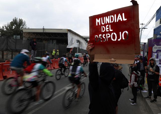 A demonstrator shows a sign that reads "World Cup of dispossession" during a protest against the Gran Tenochtitlan bike path and the organisation of the World Cup in Mexico City on April 19, 2026. The Gran Tenochtitlan is an infrastructure project designed to connect Banorte Stadium (formerly Azteca Stadium) with other points of interest in Mexico City, according to the local government. (Photo by LUIS CORTES / AFP)
