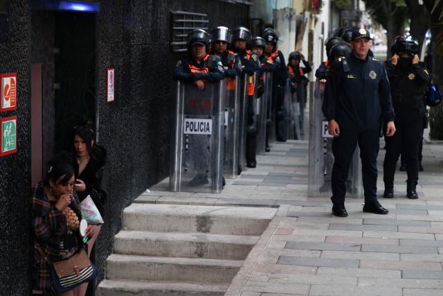 Mexican riot police officers stand guard during a protest by sex workers against the Gran Tenochtitlan bike path and the organisation of the World Cup in Mexico City on April 19, 2026. The Gran Tenochtitlan is an infrastructure project designed to connect Banorte Stadium (formerly Azteca Stadium) with other points of interest in Mexico City, according to the local government. (Photo by LUIS CORTES / AFP)