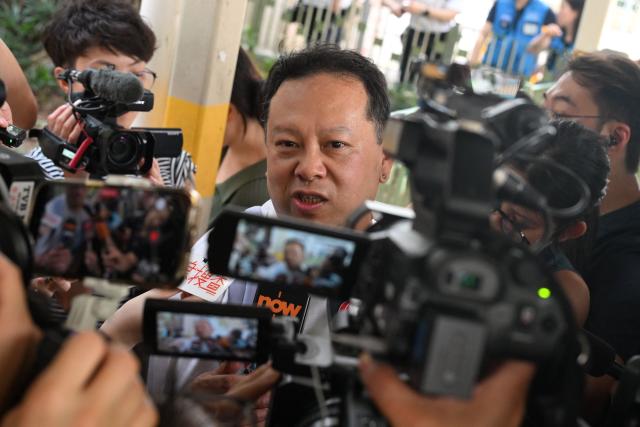 Steven Chong, a resident of Wang Fuk Court estate, talks to the media carrying items that he retrieved from his fire damaged apartment in Hong Kong on April 20, 2026. Thousands of Hong Kong residents who lost their homes in a massive fire last year are set to return from April 20 for the first time to collect what is left of their belongings. (Photo by Peter PARKS / AFP)