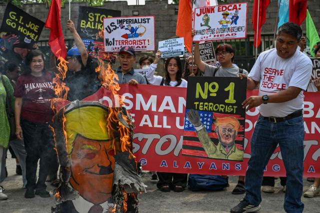 Protesters hold up a sign and burn an image of US President Donald Trump during a protest against the Balikatan joint military exercises between the Philippines and the US, outside Camp Aguinaldo in Quezon City, metro Manila on April 20, 2026. (Photo by Jam STA ROSA / AFP)