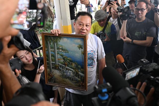 Steven Chong, a resident of Wang Fuk Court estate, shows the media items that he retrieved from his fire damaged apartment in Hong Kong on April 20, 2026. Thousands of Hong Kong residents who lost their homes in a massive fire last year are set to return from April 20 for the first time to collect what is left of their belongings. (Photo by Peter PARKS / AFP)