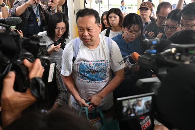 Steven Chong, a resident of Wang Fuk Court estate, talks to the media carrying items that he retrieved from his fire damaged apartment in Hong Kong on April 20, 2026. Thousands of Hong Kong residents who lost their homes in a massive fire last year are set to return from April 20 for the first time to collect what is left of their belongings. (Photo by Peter PARKS / AFP)
