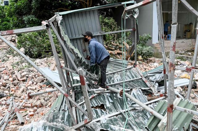 A worker dismantles corrugated metal sheets at a building demolition site in Hanoi on April 20, 2026. (Photo by Nhac NGUYEN / AFP)