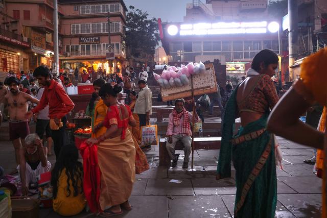 A cotton candy seller waits for customers as devotees change after taking a dip in the river Ganges at Dashashwamedh Ghat in Varanasi on April 20, 2026. (Photo by Niharika KULKARNI / AFP)