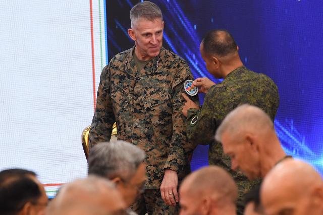 Major General Francisco Lorenzo (R), Philippine exercise director puts an exercise patch on US Lieutenant General Christian Wortman (L) Commanding General I Marine Expedetionary Force, during the opening ceremony of the annual Balikatan (shoulder to shoulder) joint military exercise at Camp Aguinaldo in Quezon city, suburban Manila on April 20, 2026. Thousands of American and Philippine troops, joined for the first time by a significant contingent of Japanese forces, began annual military exercises on April 20 set against the backdrop of the Middle East war. (Photo by Ted ALJIBE / AFP)