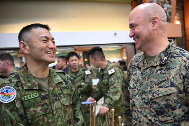 Major General Toshikatu Musha (L) of Japan's Self-Defense Forces, talks to a US marine officer during the opening ceremony of the annual Balikatan (shoulder to shoulder) joint military exercise at Camp Aguinaldo in Quezon city, suburban Manila on April 20, 2026. Thousands of American and Philippine troops, joined for the first time by a significant contingent of Japanese forces, began annual military exercises on April 20 set against the backdrop of the Middle East war. (Photo by Ted ALJIBE / AFP)