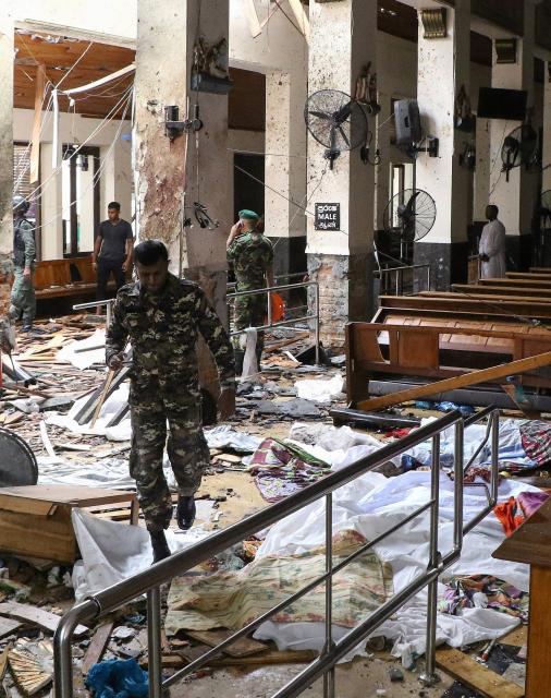EDITORS NOTE: Graphic content / (FILES) Sri Lankan security personnel walk past dead bodies covered with blankets amid blast debris at St. Anthony's Shrine following an explosion in the church in Kochchikade in Colombo on April 21, 2019. Seven years after Sri Lanka's Easter Sunday bomb blasts that killed 279 people, survivors still bear deep physical and emotional scars in 2026, compounded by the failure of successive governments to deliver justice. (Photo by ISHARA S.  KODIKARA / AFP)