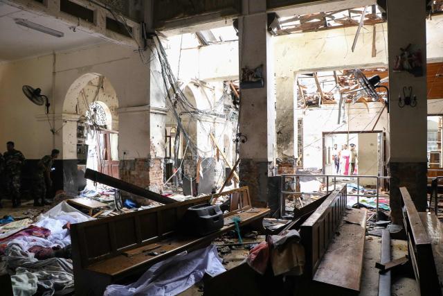 EDITORS NOTE: Graphic content / (FILES) Sri Lankan security personnel walk past dead bodies covered with blankets amid blast debris at St. Anthony's Shrine following an explosion in the church in Kochchikade in Colombo on April 21, 2019. Seven years after Sri Lanka's Easter Sunday bomb blasts that killed 279 people, survivors still bear deep physical and emotional scars in 2026, compounded by the failure of successive governments to deliver justice. (Photo by ISHARA S.  KODIKARA / AFP)