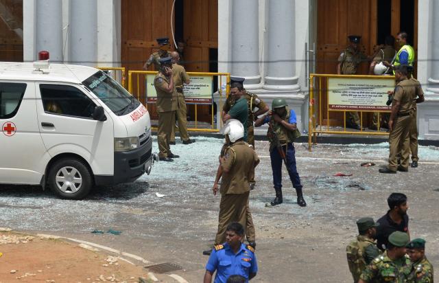(FILES) Sri Lankan security personnel stand next to an ambulance outside St. Anthony's Shrine in Kochchikade in Colombo on April 21, 2019 following a blast at the church. Seven years after Sri Lanka's Easter Sunday bomb blasts that killed 279 people, survivors still bear deep physical and emotional scars in 2026, compounded by the failure of successive governments to deliver justice. (Photo by ISHARA S.  KODIKARA / AFP)