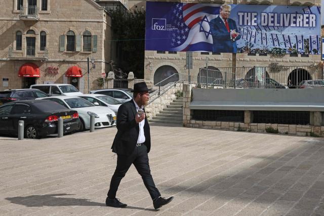 A man walks past a banner depicting US President Donald Trump with the slogan “The Deliverer” in Jerusalem on April 20, 2026. Iran is not currently planning to attend talks with the United States, state media said, after the US president ordered US negotiators to travel to Pakistan on April 20, just days before a ceasefire in the Middle East expires. (Photo by AHMAD GHARABLI / AFP) / 