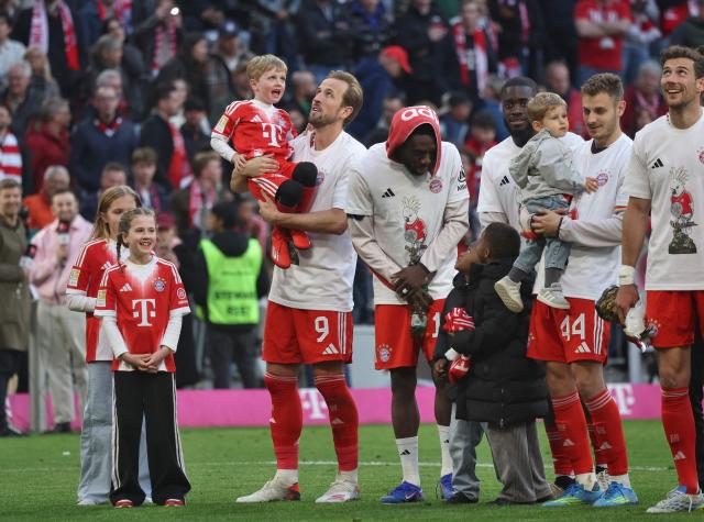 Bayern Munich's English forward #09 Harry Kane (4thL) with his children, Bayern Munich's Canadian defender #19 Alphonso Davies, Bayern Munich's French defender #02 Dayot Upamecano, Bayern Munich's Croatian defender #44 Josip Stanisic and Bayern Munich's German midfielder #08 Leon Goretzka celebrate after winning the German first division Bundesliga football match between FC Bayern Munich and VfB Stuttgart as well as the Bundesliga title in Munich, southern Germany, on April 19, 2026. Bayern Munich cruised to a 4-2 home win over Stuttgart and claim a record-extending 35th Bundesliga title. (Photo by Karl-Josef HILDENBRAND / AFP) / DFL REGULATIONS PROHIBIT ANY USE OF PHOTOGRAPHS AS IMAGE SEQUENCES AND/OR QUASI-VIDEO