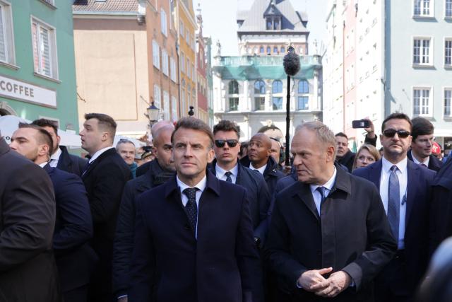 French President Emmanuel Macron (C-L) is welcomed by Poland's Prime Minister Donald Tusk (C-R) at the Golden Gate (Zlota Brama) in the city centre of Gdansk, Poland, on April 20, 2026, at the start of his one-day-visit to Poland. (Photo by Ludovic MARIN / AFP)
