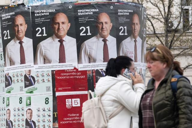 Pedestrians walk past election posters of the Progressive Bulgaria coalition's leader and former President Rumen Radev in Sofia on April 20, 2026. Bulgaria held its eighth legislative election in five years, with ex-president Rumen Radev's grouping tipped to win on a pledge to fight corruption, after an anti-graft movement triggered a long political crisis. (Photo by Nikolay DOYCHINOV / AFP)