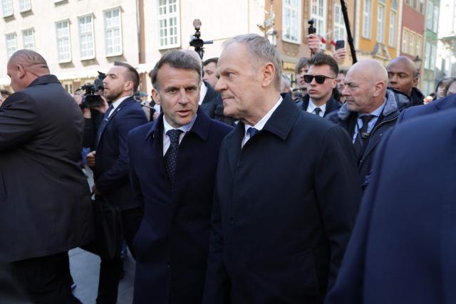 French President Emmanuel Macron (L) and Poland's Prime Minister Donald Tusk (R) chat as they walk in the city centre of Gdansk, Poland, on April 20, 2026, at the start of his one-day-visit to Poland. (Photo by Ludovic MARIN / AFP)