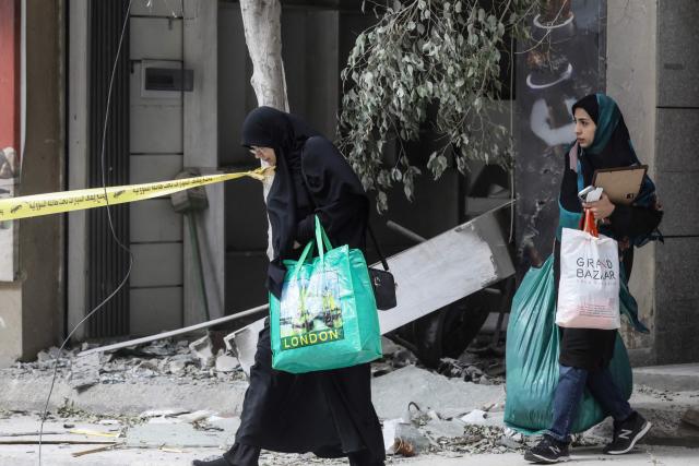 Women carrying belongings walk past the debris of a destroyed building in the Haret Hreik area of Beirut’s southern suburbs during a media tour organised by Iran-backed militant group Hezbollah on April 20, 2026. Lebanon was drawn into the Middle East war on March 2 when Hezbollah launched attacks on Israel to avenge the killing of the Iranian leader. Israel has responded with broad strikes across Lebanon and a ground offensive. (Photo by IBRAHIM AMRO / AFP) / 