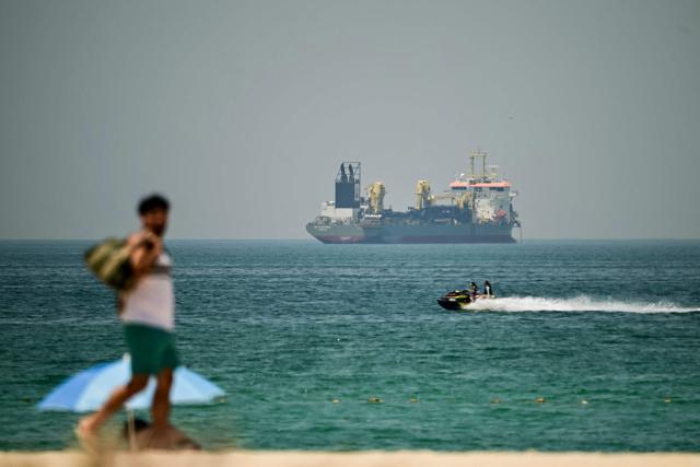 TOPSHOT - A commercial vessel is seen off the coast of Dubai on April 20, 2026. Oil prices jumped sharply on April 20 over fears hostilities could resume in the weeks-long war, after Iran closed the Strait of Hormuz again over the weekend following its brief reopening on Friday in recognition of a ceasefire in Lebanon. (Photo by AFP) / 