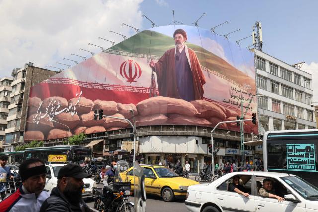 Commuters drive past a large billboard depicting Iran's Supreme Leader Ayatollah Mojtaba Khamenei on a street in Tehran on April 20, 2026. Iran insisted it has no plan to attend a new round of negotiations with the United States on April 20, as uncertainty grows over a push to stop the Middle East war from resuming. The US president said he was sending negotiators to Pakistan for talks on ending the war that engulfed the region and rattled global markets, while repeating threats to attack Iran's energy infrastructure if it did not make a deal. (Photo by ATTA KENARE / AFP) / 