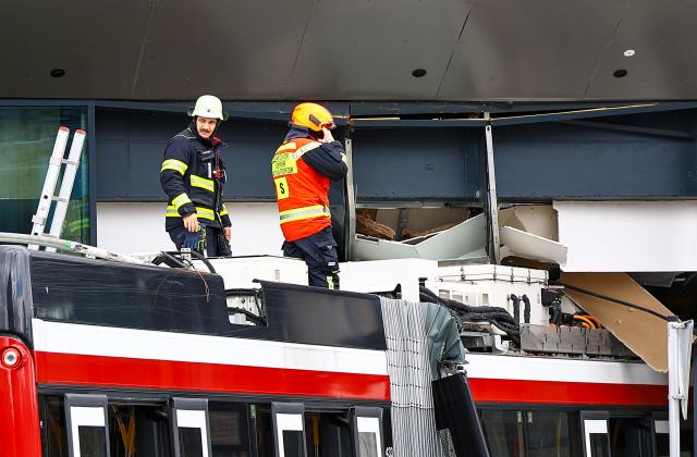 Firefighters stand on the roof of a trolleybus that crashed into a supermarket on April 20, 2026 in Salzburg, Austria, killing one person and injuring seven peaple, two of them severely. (Photo by various sources / AFP) / Austria OUT