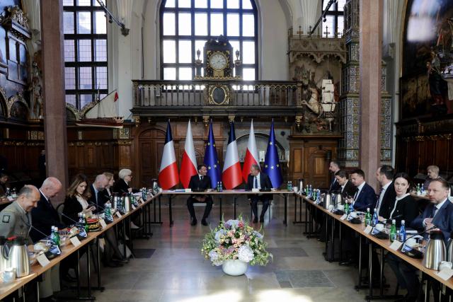 French President Emmanuel Macron (C-L), Poland's Prime Minister Donald Tusk (C-R), France's Defence Minister Catherine Vautrin (6L), Polish Defence Minister Wladyslaw Kosiniak-Kamysz (6R), French Foreign Minister Jean-Noel Barrot (4L), French Chief of Military staff Vincent Giraud (L) and other members of the French and Polish delegation attend a plenary session in the Great Hall at the Artus Court (Dwor Artusa) in Gdansk, Poland, on April 20, 2026 during the French President's one-day visit to Poland. (Photo by Ludovic MARIN / AFP)