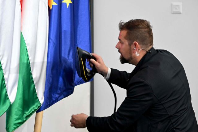 A man irons a flag of the European Union (EU) as preparations are under way for a press conference of Hungary's TISZA party following the first official meeting of TISZA's new parliamentary group at the HUNGEXPO Congress and Exhibition Center in Budapest, Hungary, on April 20, 2026. Hungary's nationalist long-time Prime Minister Viktor Orban lost on April 12, 2026 to political newcomer, conservative pro-EU Peter Magyar, whose party won a two-thirds parliamentary majority in a vote marked by record turnout in the central European country. (Photo by Attila KISBENEDEK / AFP)