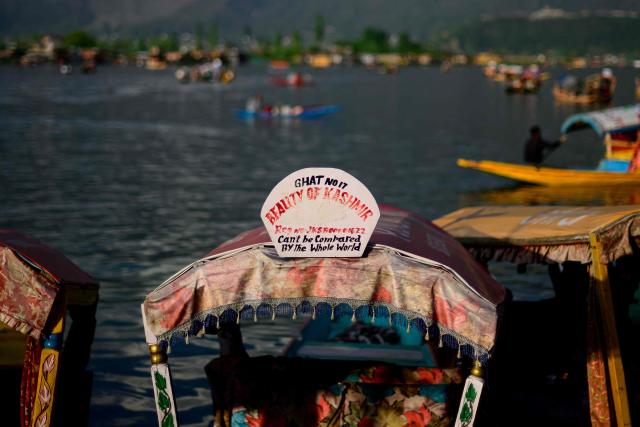 A signboard reading "Beauty of Kashmir" is seen on top of a Shikara, a traditional wooden boat at the iconic Dal Lake in Srinagar on April 20, 2026. In the once-booming resort towns of India-controlled Kashmir, hoteliers are switching on the lights to welcome a trickle of visitors, a year after militants opened fire on holidaymakers in an attack that killed 26 people. (Photo by Manan VATSYAYANA / AFP)
