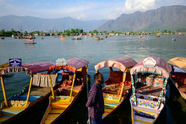 A boatman waits for customers to ride Shikara, a traditional wooden boat at the iconic Dal Lake in Srinagar on April 20, 2026. In the once-booming resort towns of India-controlled Kashmir, hoteliers are switching on the lights to welcome a trickle of visitors, a year after militants opened fire on holidaymakers in an attack that killed 26 people. (Photo by Manan VATSYAYANA / AFP)