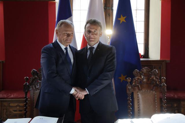 CORRECTION / French President Emmanuel Macron and Poland's Prime Minister Donald Tusk shake hands at the signing of the golden book at the Main Town Hall in Gdansk, Poland, on April 20, 2026 during the French President's one-day-visit to Poland. (Photo by Ludovic MARIN / AFP) / “The erroneous mention[s] appearing in the metadata of this photo by Ludovic MARIN has been modified in AFP systems in the following manner: [Main Town Hall] instead of [the Artus Court (Dwor Artusa)]. Please immediately remove the erroneous mention[s] from all your online services and delete it (them) from your servers. If you have been authorized by AFP to distribute it (them) to third parties, please ensure that the same actions are carried out by them. Failure to promptly comply with these instructions will entail liability on your part for any continued or post notification usage. Therefore we thank you very much for all your attention and prompt action. We are sorry for the inconvenience this notification may cause and remain at your disposal for any further information you may require.”
