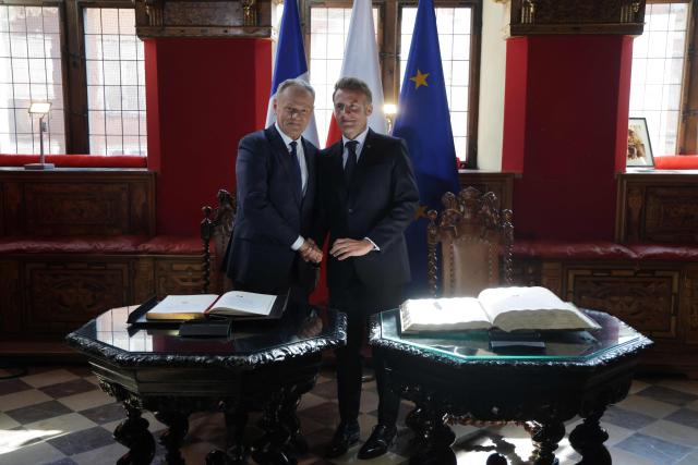 French President Emmanuel Macron (R) and Poland's Prime Minister Donald Tusk shake hands at the signing of the golden book at the Main Town Hall in Gdansk, Poland, on April 20, 2026 during the French President's one-day-visit to Poland. (Photo by Ludovic MARIN / AFP)