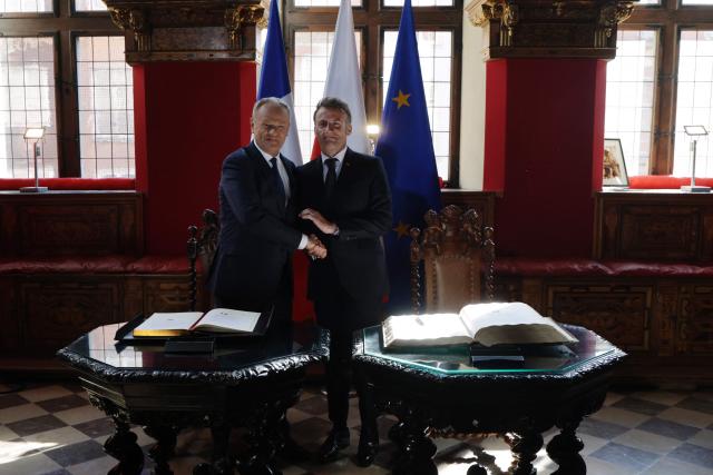French President Emmanuel Macron (R) and Poland's Prime Minister Donald Tusk shake hands at the signing of the golden book at the Main Town Hall in Gdansk, Poland, on April 20, 2026 during the French President's one-day-visit to Poland. (Photo by Ludovic MARIN / AFP)