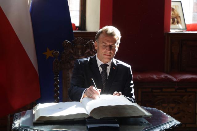 French President Emmanuel Macron signs the golden book at the Main Town Hall in Gdansk, Poland, on April 20, 2026 during the French President's one-day-visit to Poland. (Photo by Ludovic MARIN / AFP)