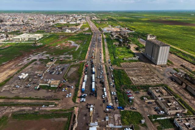 This aerial picture shows cars and trucks loaded with goods waiting to cross over into Syria at the al-Rabia border crossing on April 20, 2026. Iraq reopened a once-bustling border crossing with Syria on Monday, more than a decade after it was closed to trade following the rise of the Islamic State group. (Photo by Zaid AL-OBEIDI / AFP)