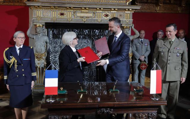 France's Defence Minister Catherine Vautrin (2ndL) and Polish Defence Minister Wladyslaw Kosiniak-Kamysz (2ndR) exchange documents after signing an agreement at the Main Town Hall in Gdansk, Poland, on April 20, 2026 during the French President's one-day visit to Poland. (Photo by Ludovic MARIN / AFP)