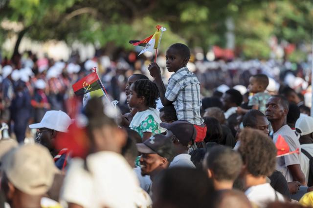 A child holds Angola and Vatican flags as a crowd gathers to wait for the arrival of Pope Leo XIV to meet with bishops at the Parish of our Lady of Fatima in Luanda on the eighth day of an 11-day apostolic journey to Africa, on April 20, 2026. (Photo by PHILL MAGAKOE / AFP)
