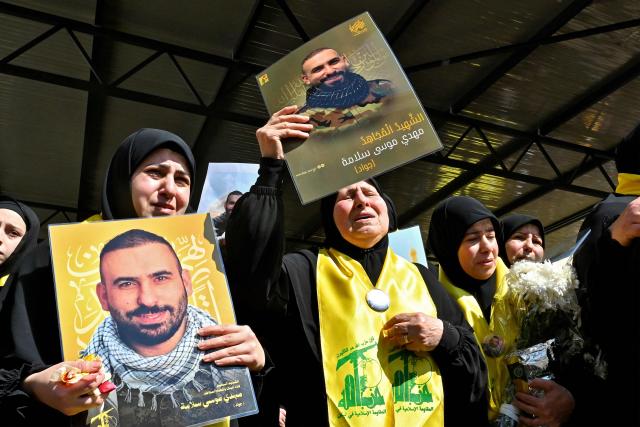 Mourners hold portraits of members of the Iran-backed militant group Hezbollah who were killed in southern Lebanon during their funeral in the Kafaat area in Beirut's southern suburbs on April 20, 2026. Hezbollah lawmaker Hassan Fadlallah said on April 20 that his group would work to break the "Yellow Line" that Israel established in southern Lebanon, adding that no one could disarm the Iran-backed group. Lebanon was drawn into the Middle East war on March 2 when Tehran-backed militant group Hezbollah launched attacks on Israel to avenge the killing of the Iranian leader. Israel has responded with broad strikes across Lebanon and a ground offensive. (Photo by FADEL itani / AFP)