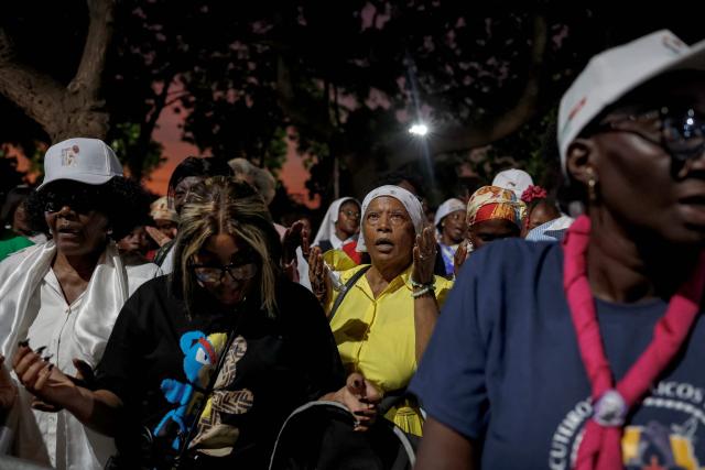 Faithfuls gathering outside gesture as Pope Leo XIV meets with bishops at the Parish of our Lady of Fatima in Luanda on the eighth day of an 11-day apostolic journey to Africa, on April 20, 2026. (Photo by PHILL MAGAKOE / AFP)