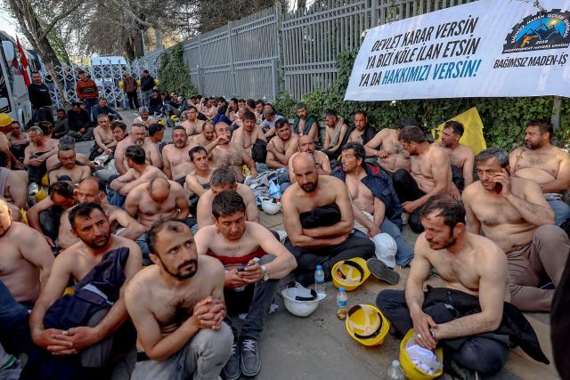 Around 90 miners stage topless a sit-in protest outside Turkey's Energy Ministry, with a banner hanged on its fence reading "Let the goverment decide: Either declare us slaves, or grant us our rights", to demand unpaid wages in Ankara, on April 20, 2026. Hundreds of workers from Doruk Mining, members of the Independent Miners' Union, walked a 180-kilometre way in nine days to reach Ankara, calling on authorities to address what they described as months of delayed payments and unresolved compensation claims. (Photo by Adem ALTAN / AFP)