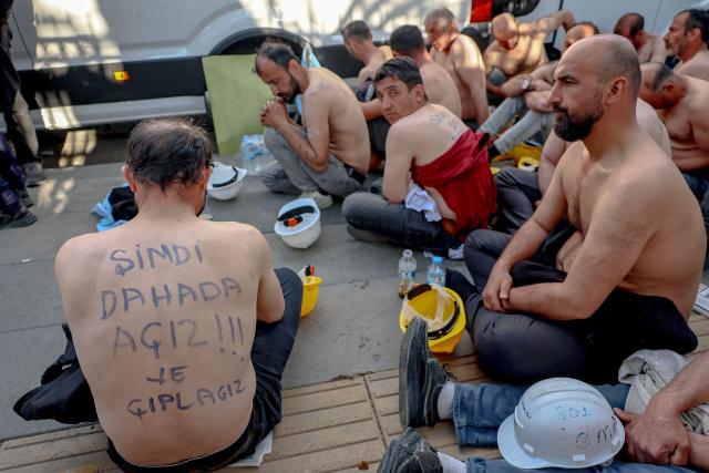 Around 90 miners stage topless a sit-in protest outside Turkey's Energy Ministry, with a slogan handwritten on the back of a demonstrator reading "Now we are even more hungry and naked", to demand unpaid wages in Ankara, on April 20, 2026. Hundreds of workers from Doruk Mining, members of the Independent Miners' Union, walked a 180-kilometre way in nine days to reach Ankara, calling on authorities to address what they described as months of delayed payments and unresolved compensation claims. (Photo by Adem ALTAN / AFP)