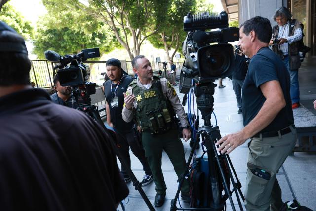 A Los Angeles County sheriff tells media to move as they search for a suspected bomb outside Los Angeles County Superior Court ahead of US singer D4vd's arraignment in Los Angeles on April 20, 2026. Rising star D4vd, whose real name is David Burke, was arrested in connection to the murder of a teenage girl whose dismembered body was found in the trunk of a car registered in the artist's name, police said on April 16. (Photo by Patrick T. Fallon / AFP)