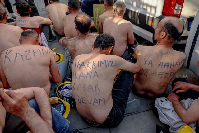 Around 90 miners stage topless a sit-in protest outside Turkey's Energy Ministry, with a slogan handwritten on the back of a demonstrator reading "We will continue until we receive our rights", to demand unpaid wages in Ankara, on April 20, 2026. Hundreds of workers from Doruk Mining, members of the Independent Miners' Union, walked a 180-kilometre way in nine days to reach Ankara, calling on authorities to address what they described as months of delayed payments and unresolved compensation claims. (Photo by Adem ALTAN / AFP)