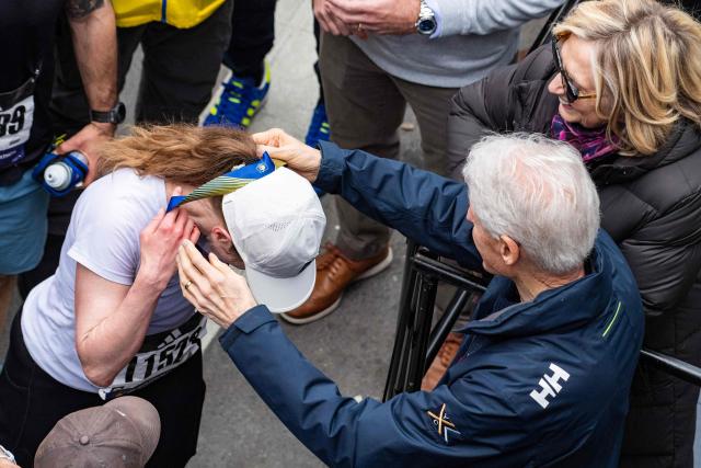 US writer Chelsea Clinton is presented a marathon medal by her parents, former US President Bill Clinton and former US Secretary of State Hillary Clinton, after crossing the finish line during the 130th Boston Marathon in Boston, Massachusetts on April 20, 2026. (Photo by Joseph Prezioso / AFP)