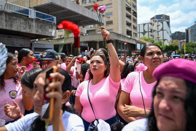 A woman supporter of Venezuela’s interim President Delcy Rodriguez holds flowers during a demonstration in Caracas on April 20, 2026, protesting against a rally held by opposition figure Maria Corina Machado in Madrid on April 19, 2026. (Photo by Juan BARRETO / AFP)