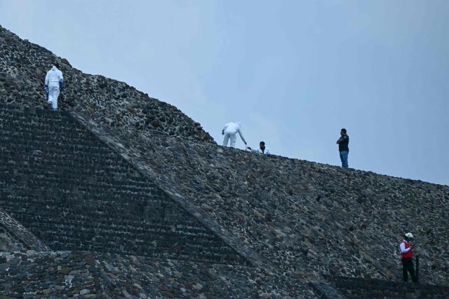Forensic experts and members of the Red Cross work on the Pyramid of the Moon at the Teotihuacan archaeological zone following a shooting in Teotihuacan, State of Mexico, on April 20, 2026. A Canadian woman was shot dead on April 20 at the Teotihuacan pyramids archaeological zone in central Mexico by a man who later killed himself, authorities said. (Photo by YURI CORTEZ / AFP)