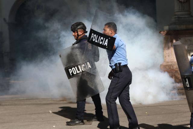 Riot police protect themselves with shields during a protest against budget cuts to university education near the National Congress in Tegucigalpa on April 20, 2026. (Photo by Johny MAGALLANES / AFP)