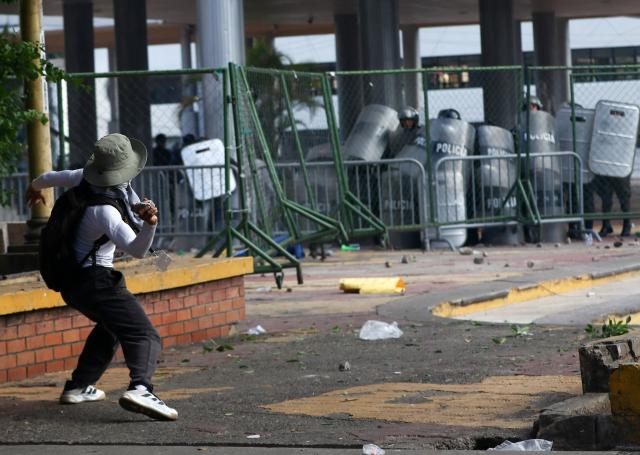 A demonstrator throws a stone at police during a protest against budget cuts to university education near the National Congress in Tegucigalpa on April 20, 2026. (Photo by Johny MAGALLANES / AFP)