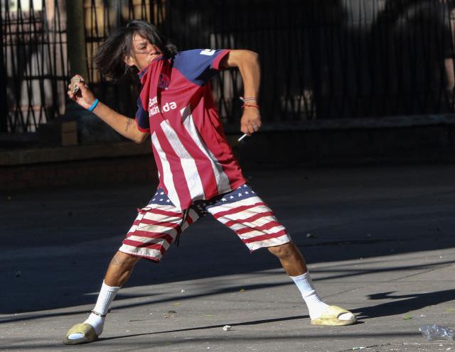 A demonstrator throws a stone at police during a protest against budget cuts to university education near the National Congress in Tegucigalpa on April 20, 2026. (Photo by Johny MAGALLANES / AFP)