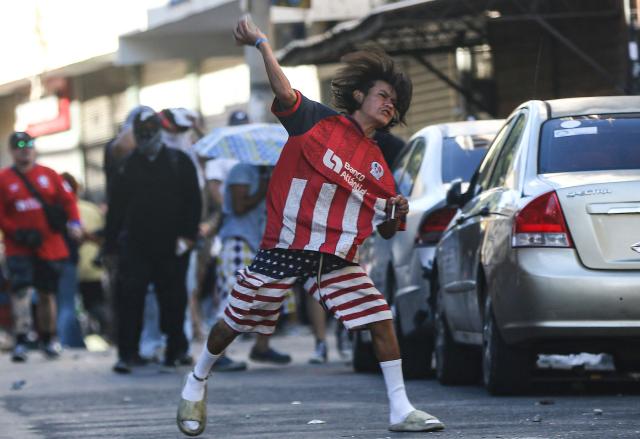A demonstrator throws a stone at police during a protest against budget cuts to university education near the National Congress in Tegucigalpa on April 20, 2026. (Photo by Johny MAGALLANES / AFP)