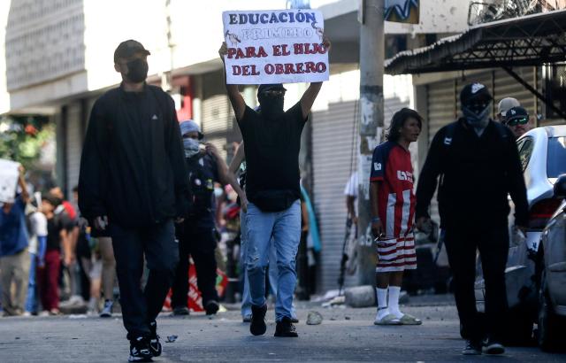 A demonstrator holds a sign reading "Education First, for the Working-Class Child" during a protest against budget cuts to university education near the National Congress in Tegucigalpa on April 20, 2026. (Photo by Johny MAGALLANES / AFP)