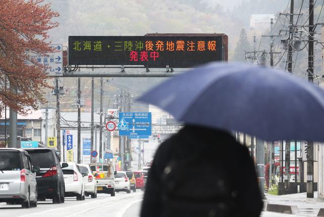An electronic signboard displaying a sign saying “Hokkaido and Off the Sanriku Coast Aftershock Advisory” early on April 21, 2026 in  Ofunato City, Iwate Prefecture. A powerful 7.7 earthquake that hit northern Japan on April 21, 2026, injured at least six people but otherwise no serious damages have been reported, the government said. (Photo by JIJI Press / AFP) / Japan OUT