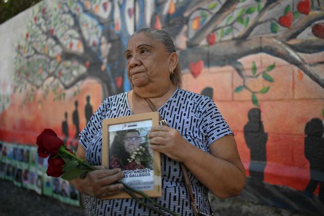 Sandra Gallegos shows a portrait of her missing son, Fernando Rosales, during the inauguration of a mural in tribute to disappeared people, at the University of El Salvador, in San Salvador, on March 19, 2026. Thousands of people went missing in the gang wars that throttled El Salvador for decades until President Nayib Bukele cracked down hard four years ago. (Photo by AFP)